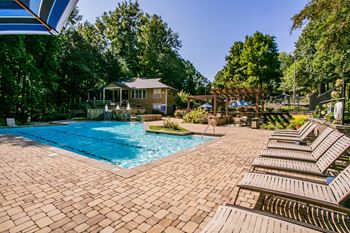 Deck with lounge chairs for sunbathing at swimming pool at park trace apartments